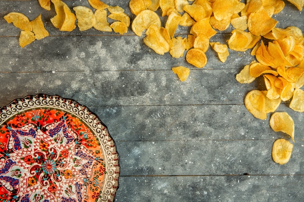 Top view of potato chips and a plate with oriental print with copy space