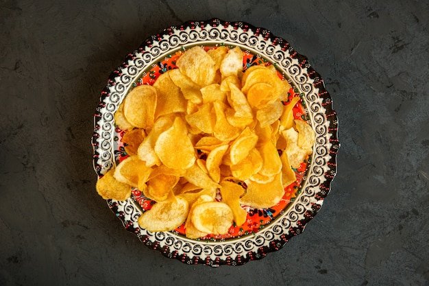 Top view of potato chips in a plate with oriental prints on black