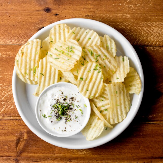 Вид сверху картофельные чипсы на тарелку с соусом