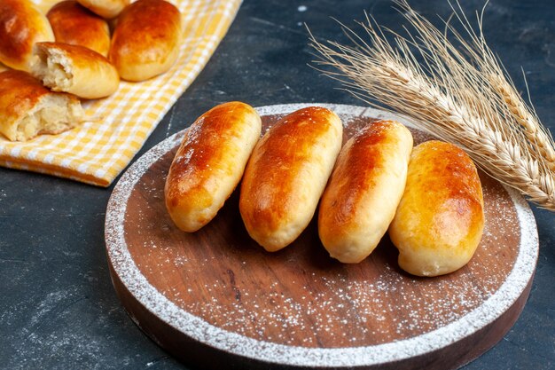 Top view potato piroshki on kitchen towel and wood board wheat on table copy space