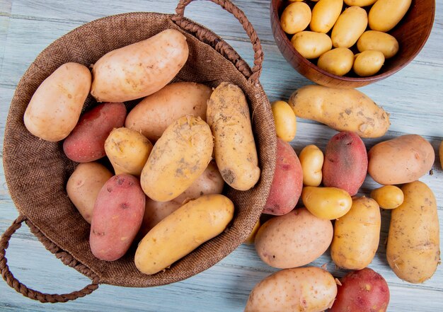 top view of potatoes in basket with new ones in bowl and others of different types on wooden surface