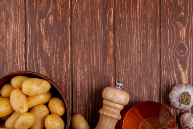 Top view of potatoes in bowl with garlic salt and butter on wood with copy space