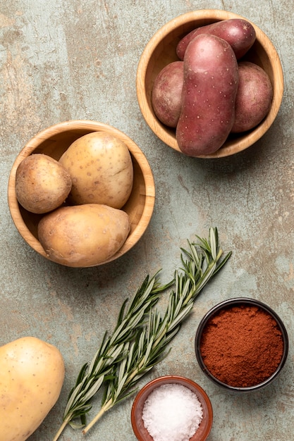 Top view of potatoes in bowls with spices and rosemary