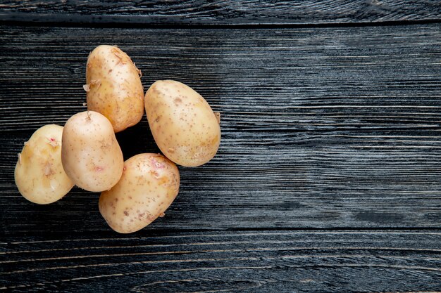 Top view of potatoes on left side and wooden background with copy space 2