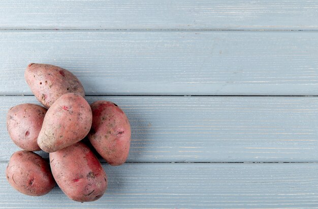 Free photo top view of potatoes on left side and wooden background with copy space