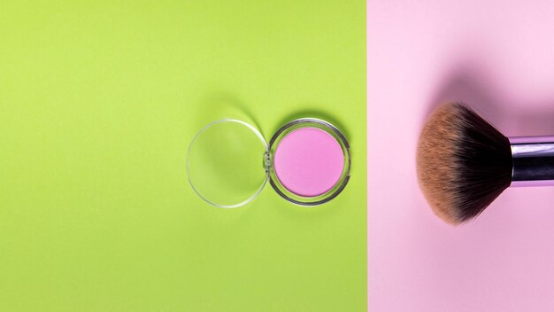 Top view of powder and brush on pink and green background