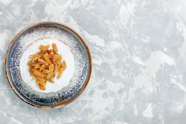 Top view  powdered raisins dried grapes inside plate on the white desk