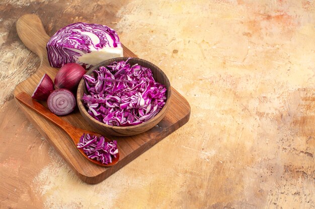 Top view preparation of fresh vegetable salad with red cabbage and onions on a cutting board on a wooden table with copy space