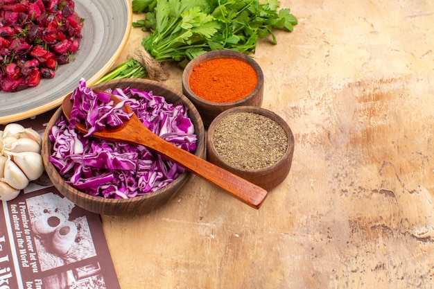 Top view prepare a bowl of chopped red cabbage togther with a bunch of parsley garlic a bowl of black pepper turmeric ground pepper for beet salad on a wooden table with copy place