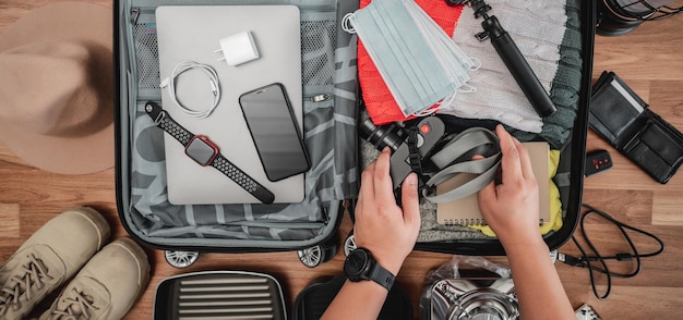 夏休み旅行のためのスーツケースの準備の上面図若い男が荷物の中のアクセサリーやものをチェックする旅行休暇と休暇のコンセプト
