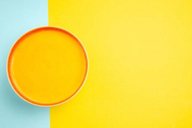 Top view of pumpkin soup inside plate on colorful background