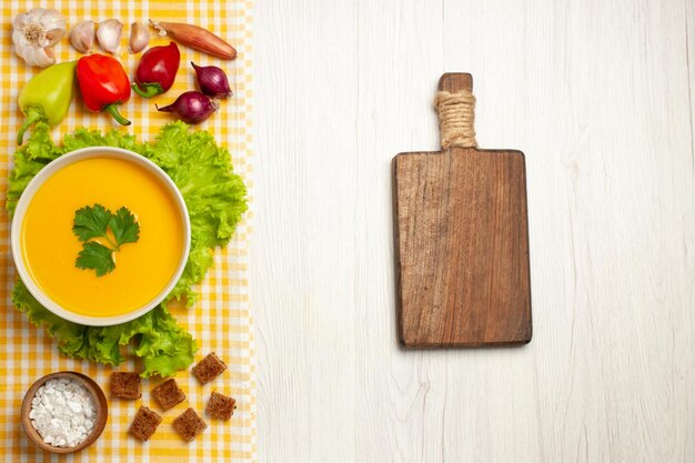 Vista dall'alto della zuppa di zucca con verdure su bianco chiaro