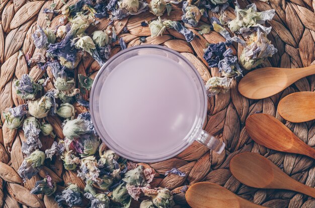 茶ハーブとスプーンの水平のトリベットの背景に平面図紫の色水