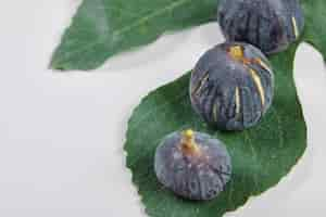 Free photo top view of purple figs with a leaf on white.