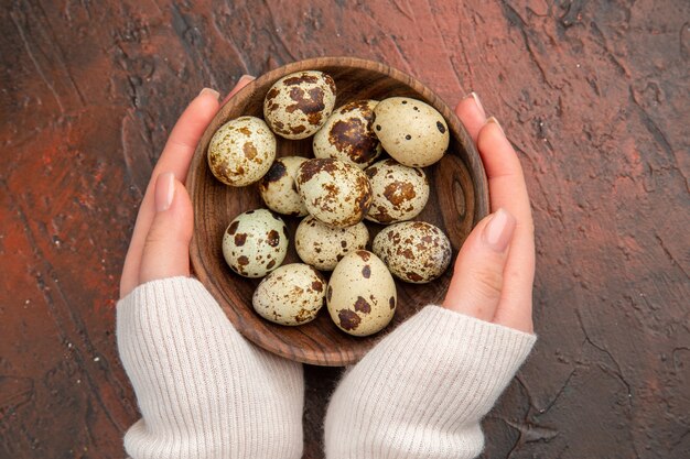 Top view quail eggs inside plate on a dark table