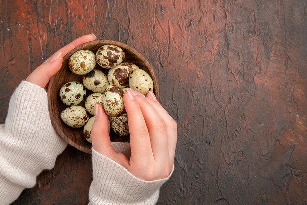 Top view quail eggs inside plate on dark table