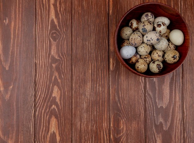 Free photo top view of quail eggs with cream colored shells with brown splotches on a wooden background with copy space