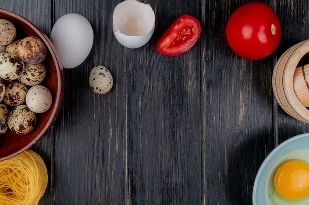 Top view of quail eggs on a wooden bowl with tomato with egg white and yolk on a wooden background with copy space