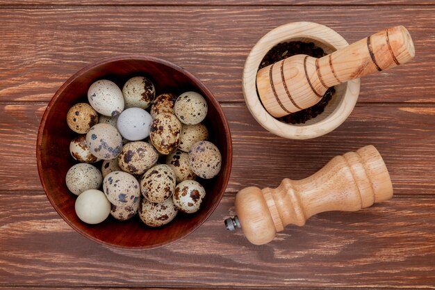 Top view of quail eggs on a wooden bowl with wooden mortar and pestle on a wooden background