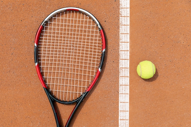 Top view racket and tennis ball on court ground