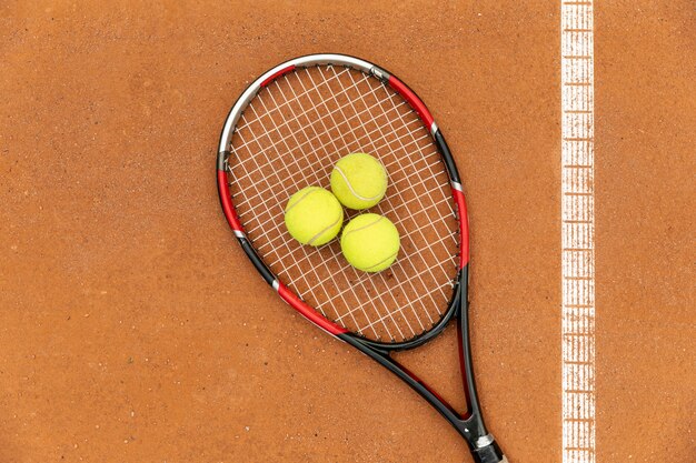 Top view racket and tennis balls on court ground