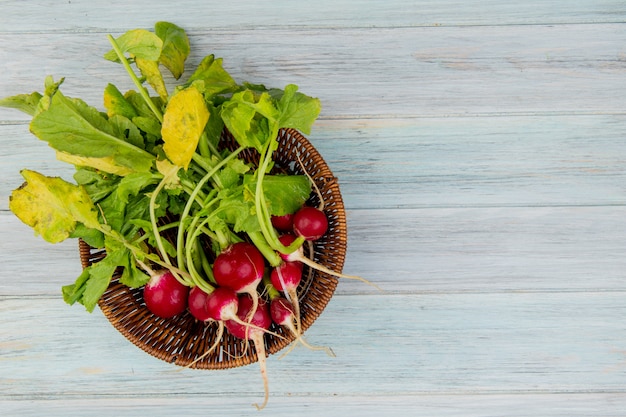 Free photo top view of radishes in basket on left side and wooden background with copy space