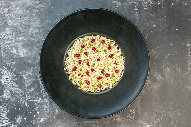 Top view ramen noodles on black round plate on dark table