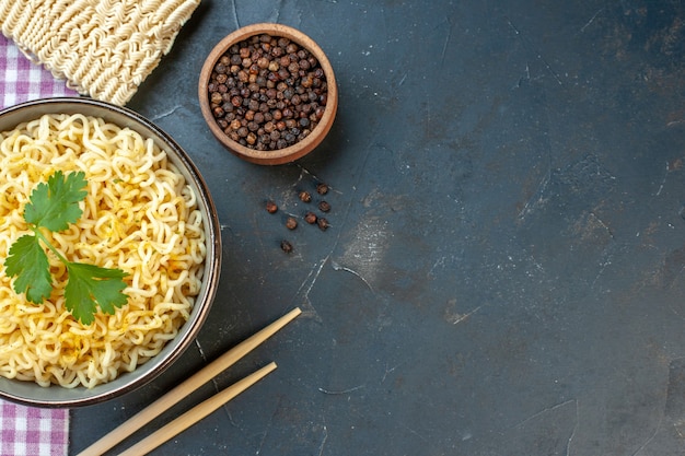 Top view ramen noodles with coriander in bowl on dark table