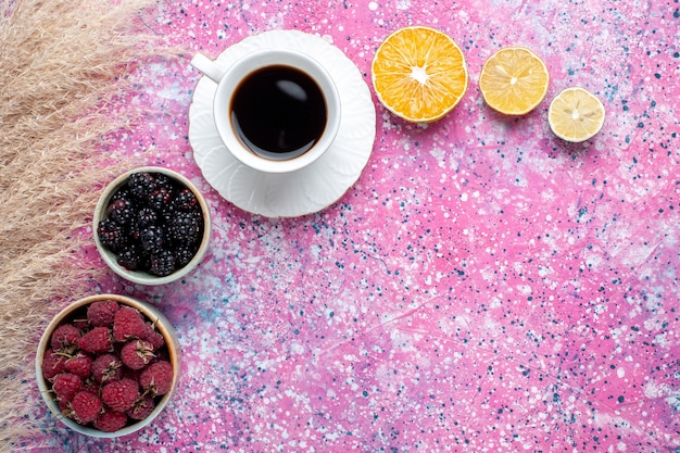 淡いピンクの表面にお茶を入れた小さな鉢の中のラズベリーとブラックベリーの上面図