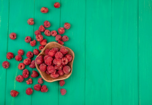 Free photo top view of raspberries in bowl and on green surface