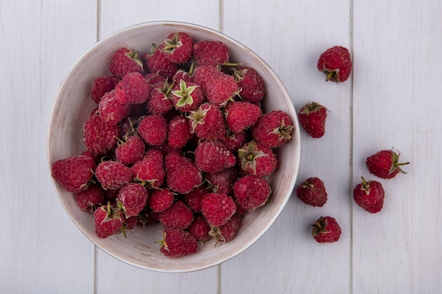 Top view of raspberries in a bowl on a white surface