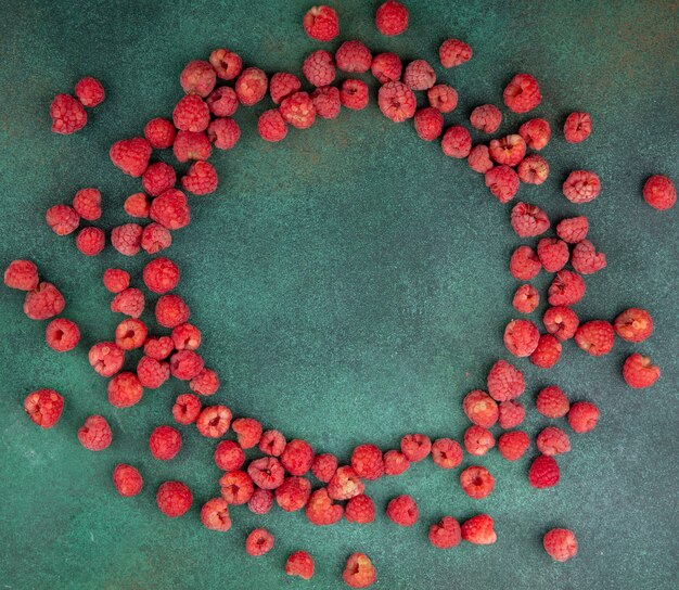 Top view of raspberries set in round shape on green surface