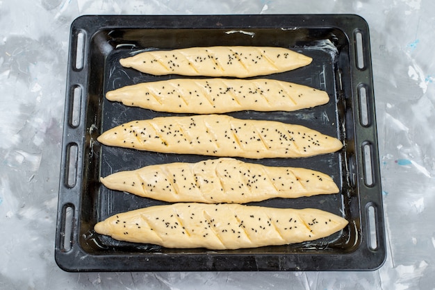 Free photo a top view raw bread dough inside black tray with oil dough bread bun bake