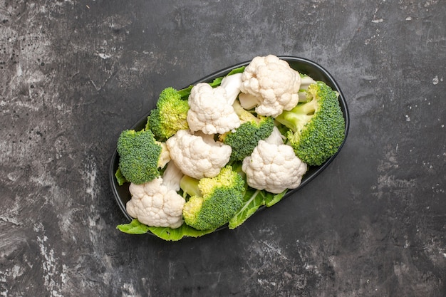 Vista dall'alto broccoli crudi e cavolfiore sul piatto ovale nero sul posto libero superficie scura