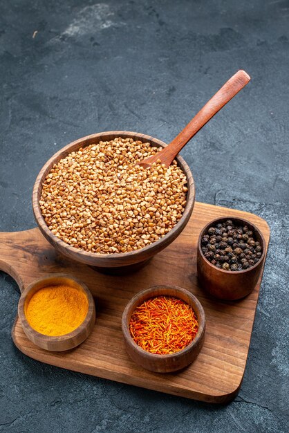 Top view raw buckwheat with seasonings on a dark-grey space