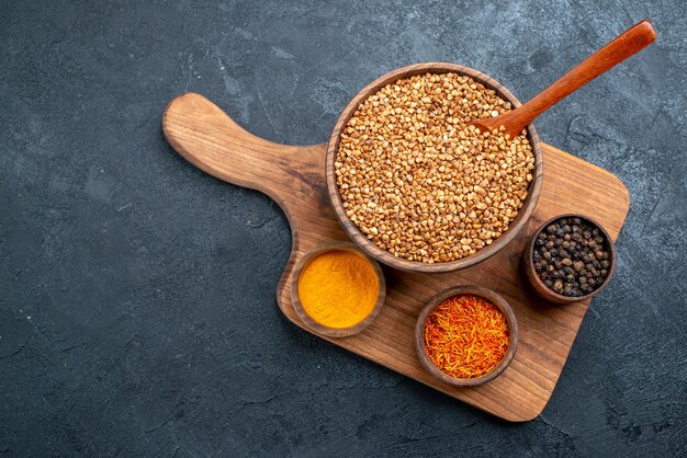 Top view raw buckwheat with seasonings on dark-grey space