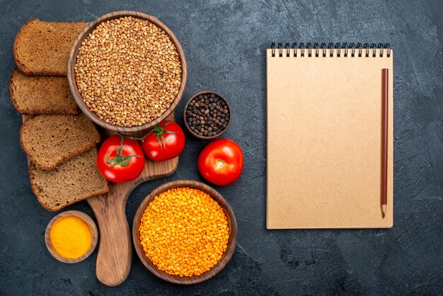 Free photo top view raw buckwheat with tomatoes and bread loafs on dark space