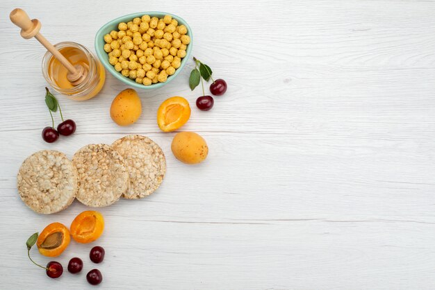 Top view raw cereals inside plate with crackers fruits and honey on white, drink milk dairy creamery breakfast