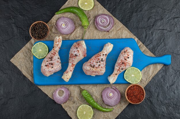 Top view raw chicken drumstick and fresh vegetables and spices.