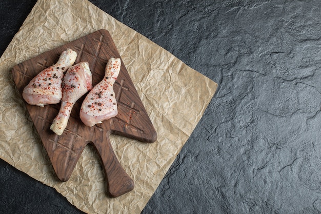 Top view raw chicken drumstick and wooden board.