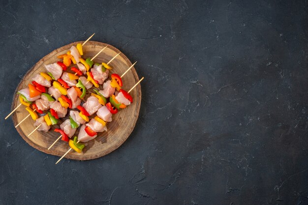 Top view raw chicken skewer on wooden board on dark table free space