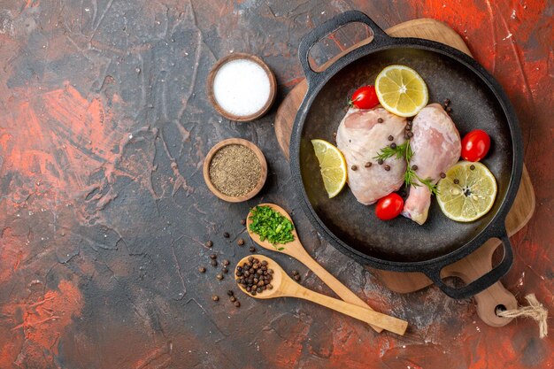 Top view raw chicken with lemon and cherry tomatoes inside pan on dark background cuisine food meat vegetable color meal dish