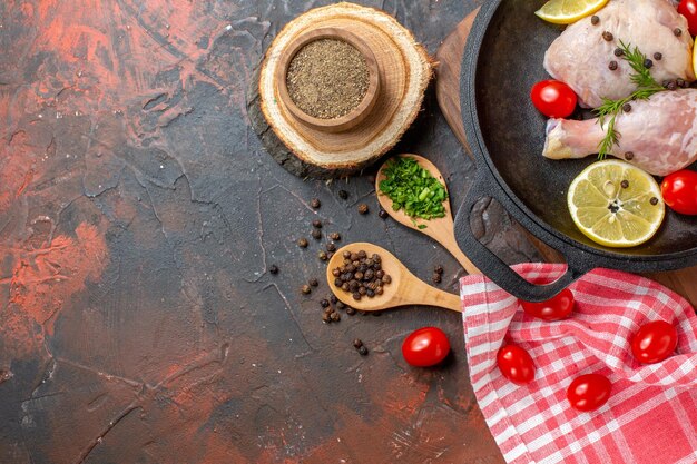 Вид сверху сырая курица с лимоном и помидорами черри внутри сковороды на темном фоне еда кухня еда мясо цвет блюдо овощи