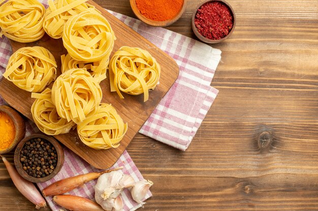 Top view raw dough flower formed pasta with different seasonings on a brown background dough meal food pasta