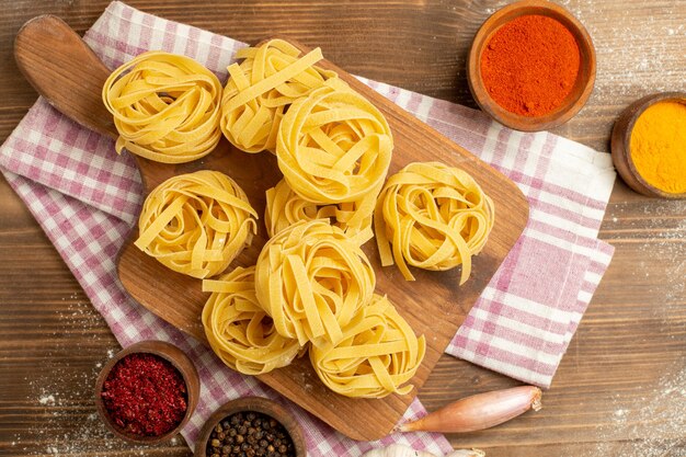 Top view raw dough flower formed pasta with seasonings on a wooden background dough meal food pasta