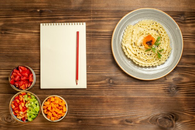 茶色の木製の背景にさまざまな調味料を使用した上面図生生地パスタ生地食品パスタミール