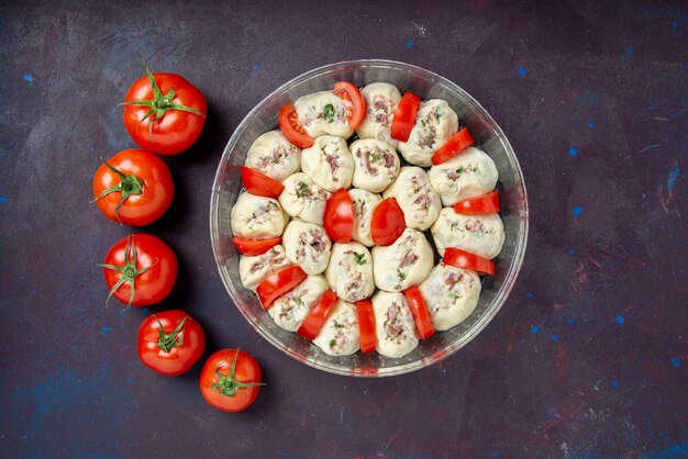 Top view raw dough pieces with ground meat and fresh red tomatoes on dark bake cuisine color photo