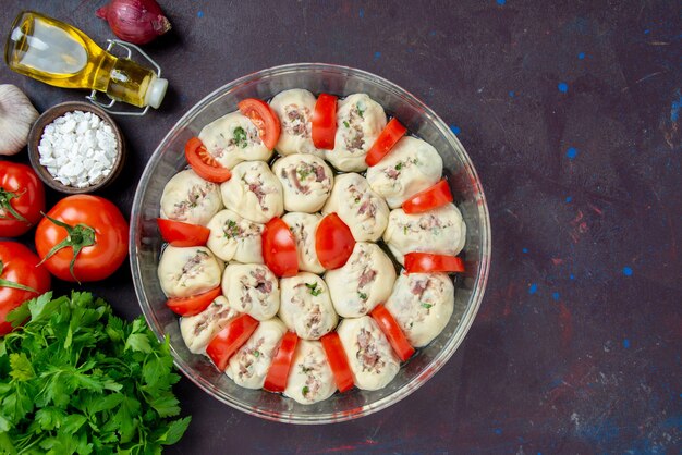 Top view raw dough pieces with ground meat greens and fresh red tomatoes on the dark meal kitchen color food photo dish cuisine