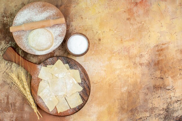 Top view raw dough slices with flour on a cream desk