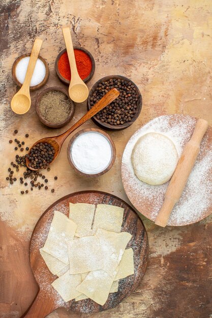 Top view raw dough slices with seasonings on a cream desk